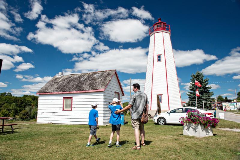 A man and two children walking toward the Historic Lighthouse
